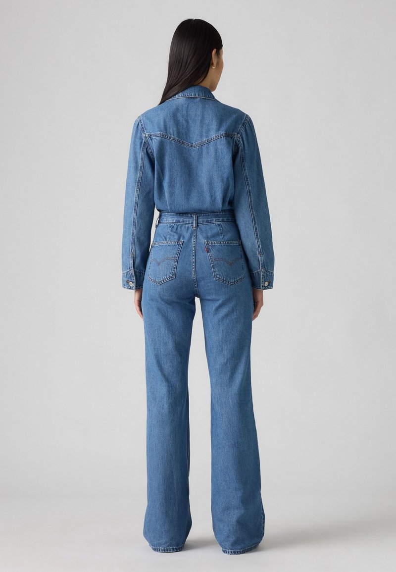 Chemise en jean et jean évasé en teinte moyenne, avec un col, des poignets boutonnés, une couture d'empiècement arrière et des poches arrière ornées de détails de couture.