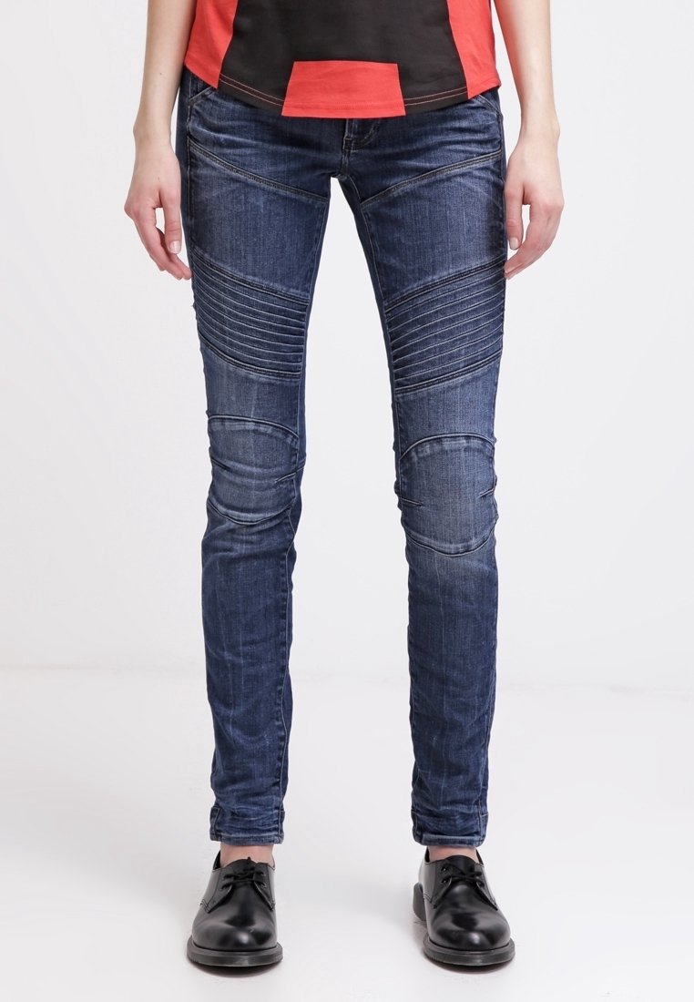 Jeans skinny de denim azul con paneles verticales texturizados y parches en las rodillas, que cuentan con un diseño clásico de cinco bolsillos y un leve efecto de desgastado.