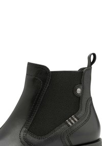 Bottes chelsea en cuir noir avec panneau élastique sur le côté, languette de tirage au talon et détail subtil en tissu rayé près de la couture.