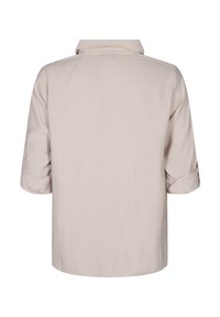 Camicia corta beige chiaro con colletto ripiegato e maniche arrotolate, realizzata in un tessuto morbido e liscio; presenta un design pulito e minimalista.