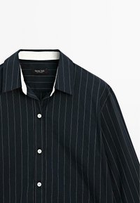 Navy blue long-sleeve shirt with white and light gray vertical stripes, a white collar, and five white buttons down the front.