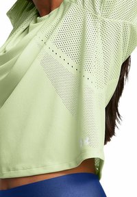 Top atlético de color verde claro, hecho de tejido transpirable, con paneles perforados y un corte holgado. Incluye el logo de Under Armour en blanco.