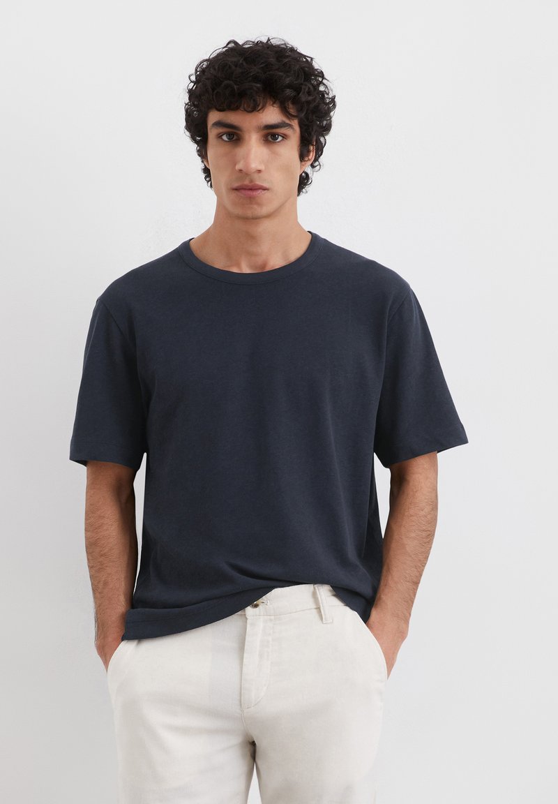 Marineblå t-shirt med rund hals lavet af blød bomuld, med korte ærmer og en afslappet pasform, parret med lysebeige bukser.