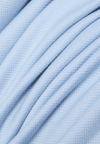 Hellblauer Stoff mit einer strukturierten Oberfläche, der diagonale Falten aufweist und sich weich sowie glatt anfühlt. Mehrere Lagen erzeugen Tiefe und Bewegung.