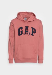 Mikina s kapucí v měkké růžové látce s velkým tmavě modrým logem GAP, přední klokanková kapsa a žebrované manžety.