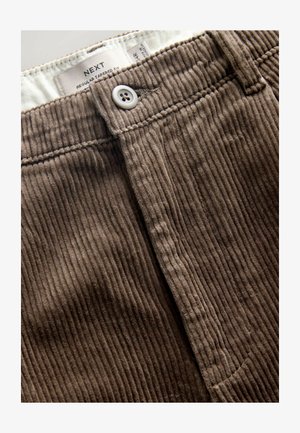 Pantaloni din corduroy maro cu o croială îngustă, textură ribbed verticală și un sistem de închidere cu un singur buton la talie.