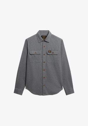 Camicia grigia a maniche lunghe realizzata in tessuto strutturato, con chiusura a bottone sul davanti, due tasche sul petto e un'etichetta nera sulla tasca sinistra.