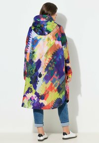 Impermeabile lungo e colorato con motivi astratti simili a pittura in viola, verde, arancione e blu. Dotato di cappuccio e vestibilità ampia.