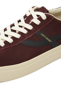 Bordo antilopne tenisice imaju kremasto vezanje, crni naglasak i teksturiranu off-white gumenu podlogu s vidljivim uzorkom.