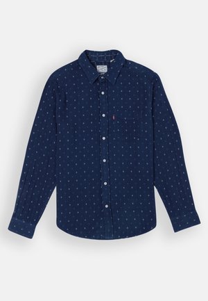 Marineblå langærmet skjorte med hvide geometriske mønstre, knap-ned krave, enkelt brystlomme og knaplukning foran.