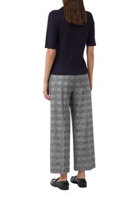 Granatowa, żebrowana bluzka na krótki rękaw w połączeniu z szerokimi szarymi spodniami w kratę i czarnymi skórzanymi butami, o luźnym kroju i teksturowanym wzorze.
