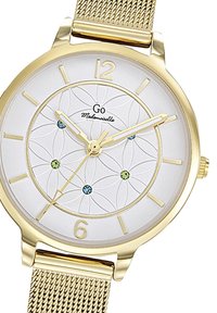 Montre en métal doré avec un cadran blanc à motifs, dotée d'indicateurs d'heure et de mains dorées, ainsi que de six pierres décoratives en bleu et vert. Bracelets en maille.