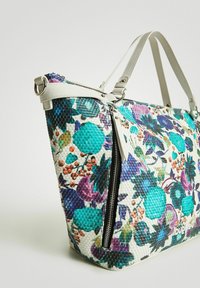 Torba torebka z kwiecistym wzorem, wykonana z plecionego materiału, z turkusowymi i fioletowymi akcentami. Białe skórzane uchwyty i detal w postaci zamykanej kieszonki.