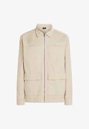 Beige kordfløjljakke med en frontlynlås, to store påsatte lommer og krave. Tekstureret stof og et enkelt design.