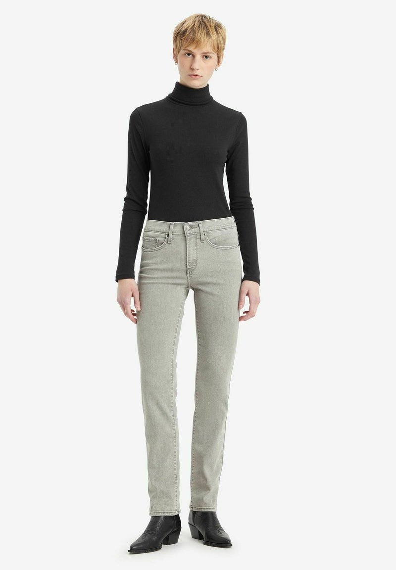 Blusa de cuello alto negra, vaqueros rectos grises, botas de tacón negras. Tejido suave, diseño ajustado y estilo clásico con mínimos detalles.