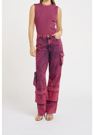Tætsiddende, ærmeløs top i mørkerosa ribbet materiale; høj talje, brede cargo-bukser i gradient pink med sidelommer og lynlåsdetaljer.