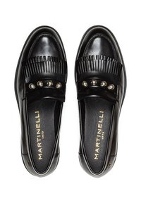 Mocasines de cuero negro con suela plana. Presentan detalles de flecos y tachuelas plateadas decorativas en la correa delantera. Textura suave.