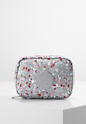 Lille rektangulær lynlåspose med røde, pink, hvide og sorte pletter på en lys grå baggrund, placeret på en hvid overflade.