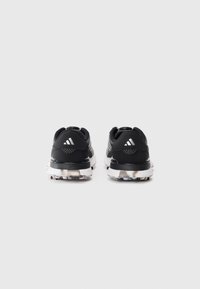 Black athletic shoes with a smooth upper, white accents, and a textured sole featuring a pattern for grip. Reinforced heel for stability.
