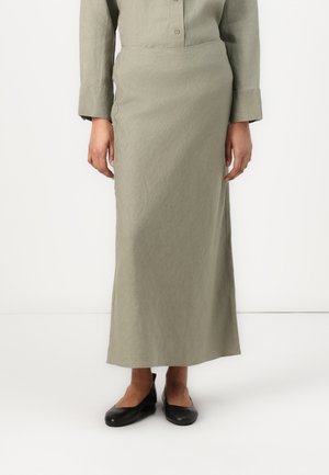 Knee-lang nederdel i olivengrøn med tekstureret finish, figursyet design og diskrete sidelommer, kombineret med sorte flade sko.