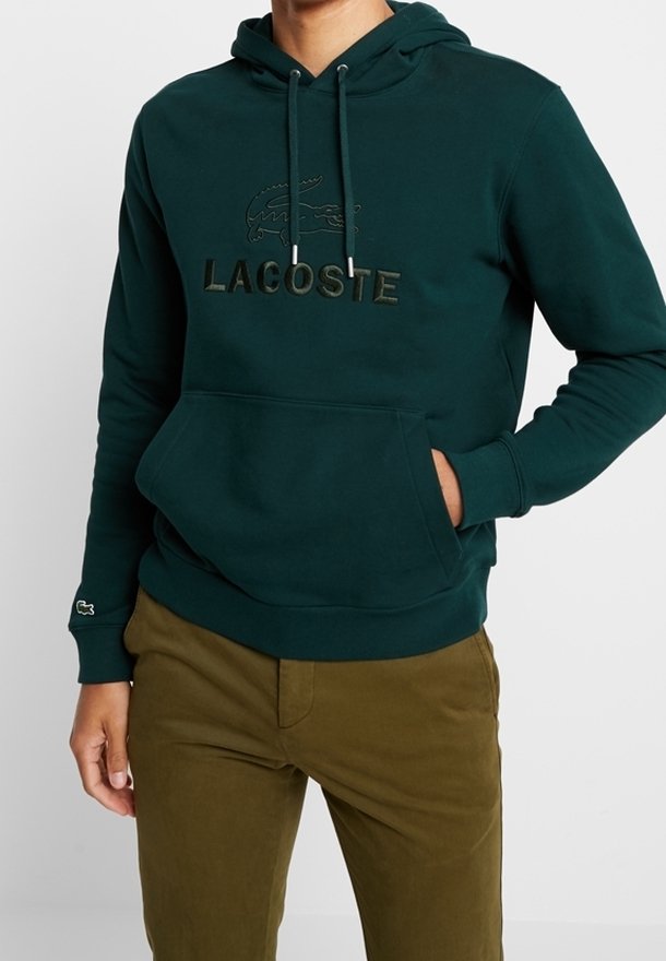 Tmavě zelená mikina s klokaní kapsou, nastavitelnými šňůrkami a embosovaným logem Lacoste. Žebrované manžety a lem. Měkčený materiál.