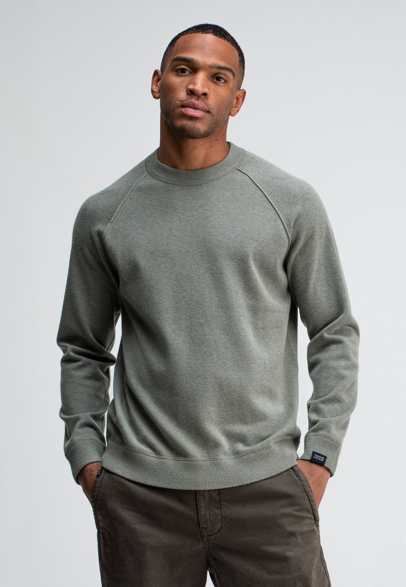 Dunkelgrüner Sweatshirt mit Rundhalsausschnitt aus weichem Material, mit gerippten Bündchen und Saum, sowie einem Etikett auf der unteren linken Seite für die Markenkennzeichnung.