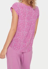 Haut rose à manches courtes avec un motif abstrait blanc et violet, col rond, coupe décontractée, en tissu léger et doux.