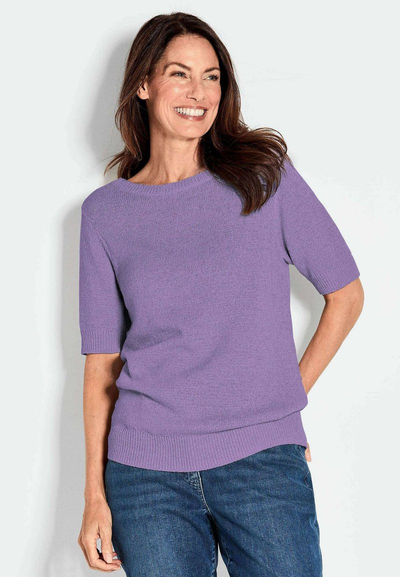 Kurzärmeliger Rundhals-Pullover aus weichem Lavendel-Strick, mit lockerem Schnitt und gerippten Bündchen und Saum, kombiniert mit blauen Jeans.