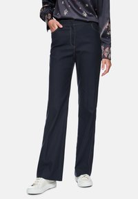 Dark blue wide-leg trousers made of denim with visible stitching and a front pocket, paired with white sneakers.