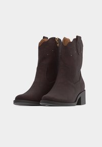 Ζευγάρι σκούρων καφέ σουέντ μπότες μέσης γάμπας με χαμηλά μπλοκ τακούνια, πλευρικά φερμουάρ και διακριτικό διακοσμητικό ράψιμο και τρουκς κοντά στην κορυφή.