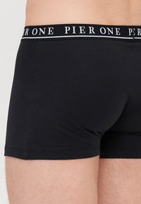 Schwarze Boxershorts aus weichem Stoff mit einem breiten elastischen Bund, der mit der Aufschrift "PIER ONE" in weißer Schrift versehen ist. Das Design legt Wert auf Komfort und Passform.