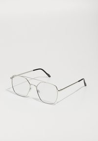 Gafas de metal plateadas con una forma geométrica octogonal, lentes transparentes y puntas negras en las patillas. Diseño minimalista con montura delgada.