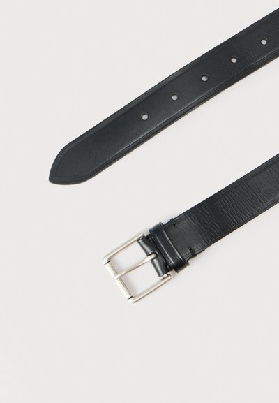 Μαύρη δερμάτινη ζώνη με υφή, ασημί αγκράφα και πολλαπλές τρύπες ρύθμισης· στενό τελείωμα για σταθερή εφαρμογή.