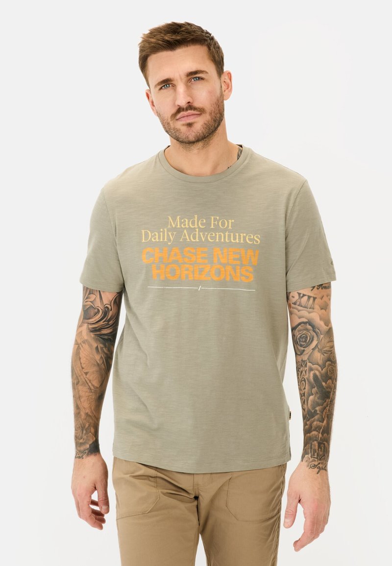 Oliven grøn kortærmet t-shirt med fed orange tekst "CHASE NEW HORIZONS", rund hals og glat, letvægtsstof.