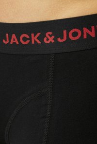 Schwarze Boxershorts für Herren mit einem schwarzen elastischen Bund, der rote "JACK & JONES" Aufschrift zeigt und eine glatte Textur mit einer figurbetonten Passform hervorhebt.