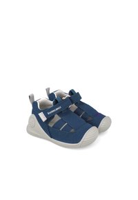 Marineblaue Kinderschuhe mit elastischen Riemen und grauen Akzenten. Aus weichem Stoff gefertigt, mit einer Gummisohle, die strukturierte Muster aufweist.