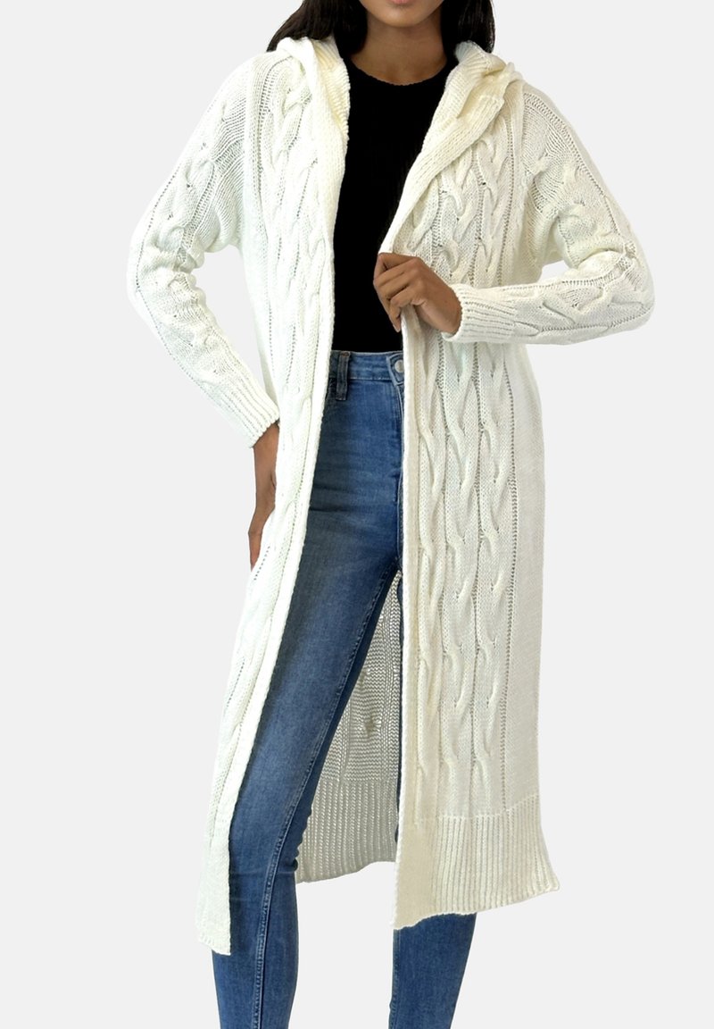 Lang wit gebreid vest met capuchon, voorzien van een kabelgebreide textuur, open voorkant en geribde boorden aan mouwen en zoom. Draagt over een zwart topje.