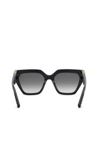 Lunettes de soleil hexagonales noires surdimensionnées avec verres gris foncé dégradés et accents dorés sur les charnières, vues de face.
