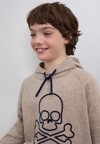 Beiger Hoodie mit einem dunkelblauen Totenkopf- und Knochen-Design. Verfügt über eine Kapuze mit Kordelzug und einen weichen, strukturierten Stoff.