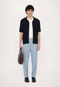 Laivastonsininen lyhythihainen napillinen paita, valkoinen T-paita, vaaleansiniset raidoitetut housut, mustat kengät, ruskea nahkalaukku. Yksinkertainen ja jämäkkä muotoilu.