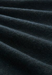 Tissu tissé sombre avec une surface texturée, présentant de légères ondulations et une couleur riche et profonde, adapté à diverses applications textiles.