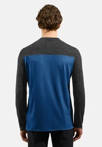 Langärmliges Hemd mit einem dunkelgrauen strukturierten Stoff an den Ärmeln und Schultern, einem einfarbigen blauen Körper und einem runden Ausschnitt.