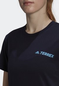 Námořnická modrá bavlněná tričko s kruhovým výstřihem. Na levé části hrudi je světle modré logo "adidas TERREX". Krátké rukávy.