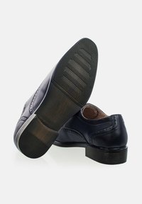 Zapatos de cuero marino con diseño de ala, suela de goma negra texturizada y corte elegante. Presentan un acabado suave y costuras decorativas.