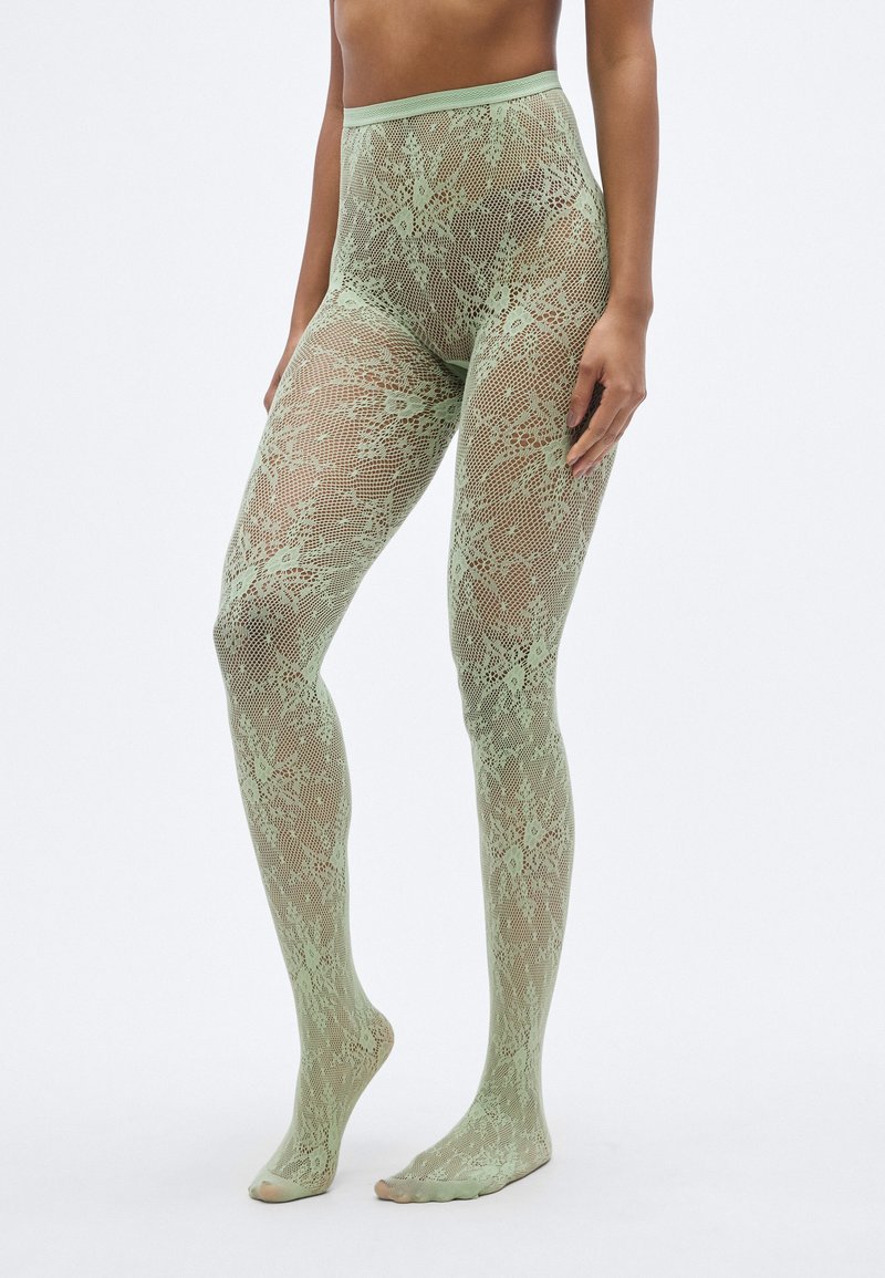 Πράσινο καλσόν δαντέλα με floral μοτίβο, ψηλή μέση και ανοιχτές μύτες. Διαφανής υφή που επιτρέπει να φαίνεται το δέρμα από κάτω.