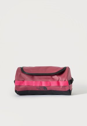 Rektangulær rød og sort toilettaske med sort kant, pink webbingstrop og The North Face-logo på forsiden.