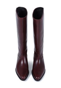 Bottes en cuir bordeaux arrivant au genou, avec un bout pointu, une texture lisse et une couture légèrement courbée le long de la tige. Design axé sur les détails.