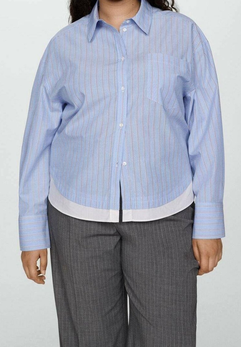 Une personne portant une chemise boutonnée à rayures bleu clair et blanches avec des manches longues et un pantalon à rayures grises.