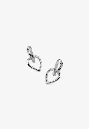 Boucles d’oreilles anneaux en argent avec pendentifs cœur ouvert ornés de petits cristaux clairs, gravées du nom de la marque « GUESS ».