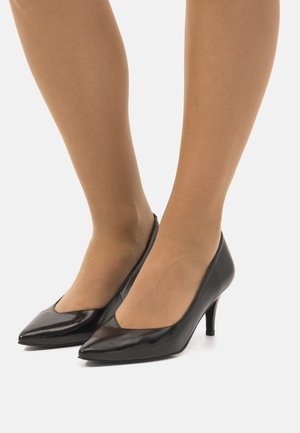 Décolleté nera in vernice con punta affusolata e tacco moderato a tronchetto. Texture liscia, design minimalista e senza motivi o decorazioni visibili.